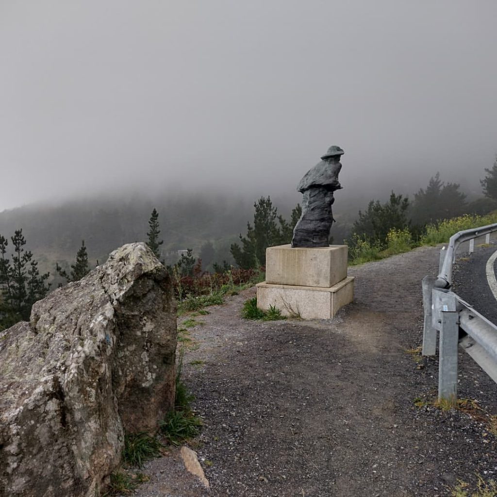 Camino con niebla al fondo y una estatua en el centro.