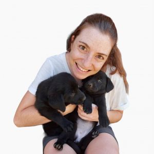 Laura sostiene en sus brazos dos cachorros de perro.