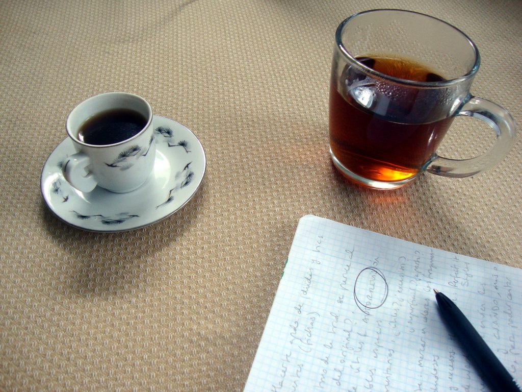 Una taza de té, una de café y una hoja sobre una mesa.