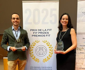Miguel Pérez Bornstein y María Galán posan con los premios FIT de Asetrad al lado de una banderola con el texto "Premios FIT 2025".